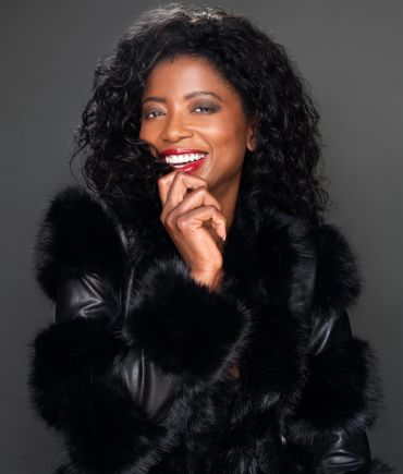 Woman in black fur coat with a joyful smile.