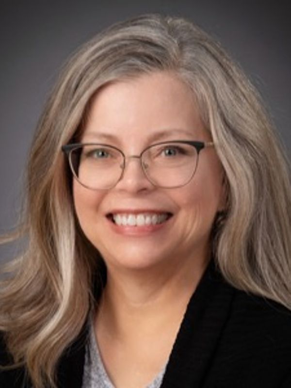 Smiling middle-aged woman with glasses and long gray hair.