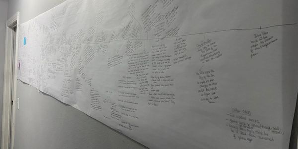 a wall with a long piece of butcher paper on it, writing on a piece of paper