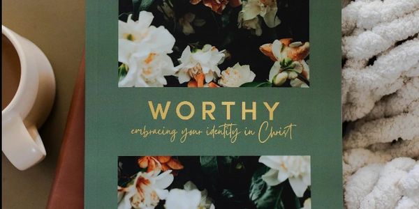 Book titled 'Worthy' with a cup of coffee and cozy blanket.