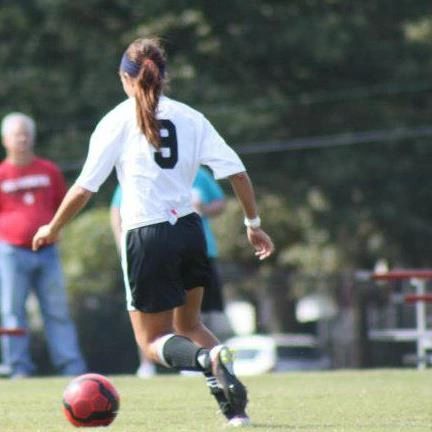 Female soccer player wearing number 9 kicking a red ball.
