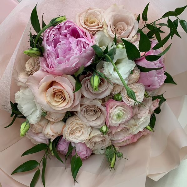Elegant bouquet of pink and cream roses with green leaves.