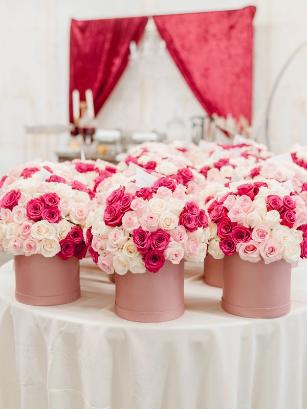 Elegant pink and white rose bouquets in round pink vases on a draped table.