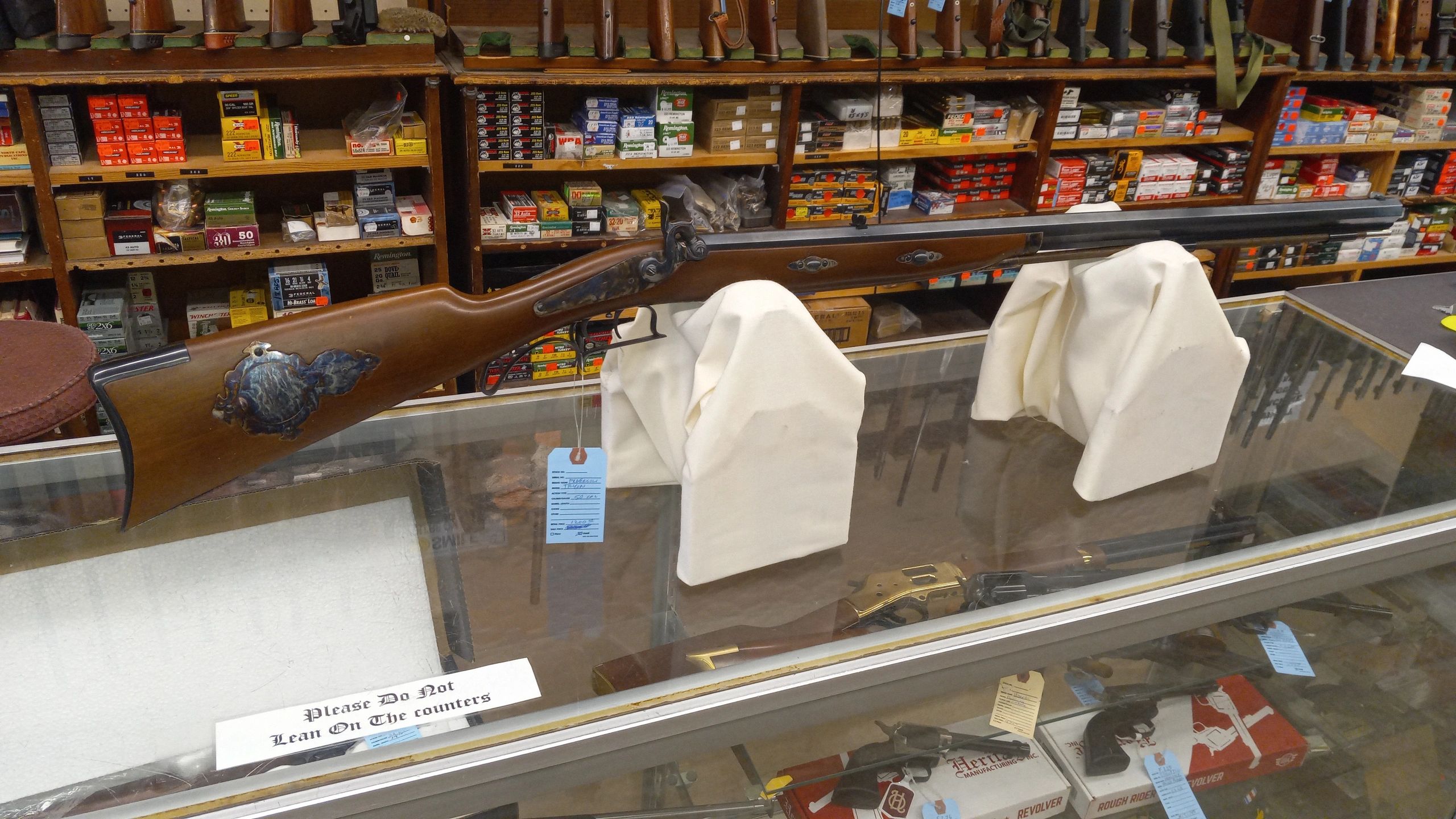 A vintage rifle displayed on a glass counter in a gun shop.