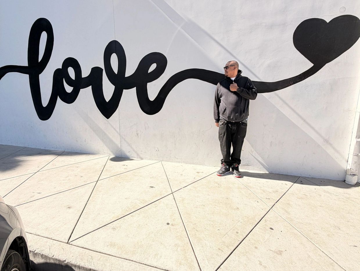 Man standing near a wall mural with the word "love" and a heart.