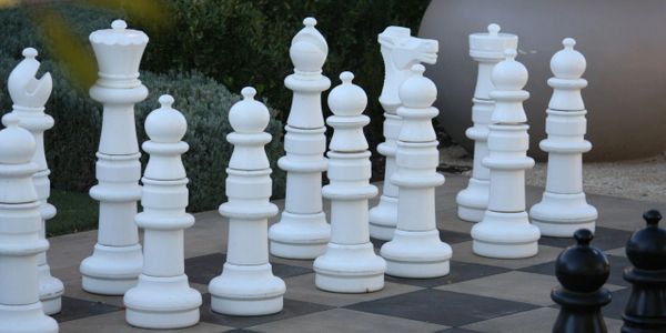 Large outdoor white chess pieces on a giant chessboard.