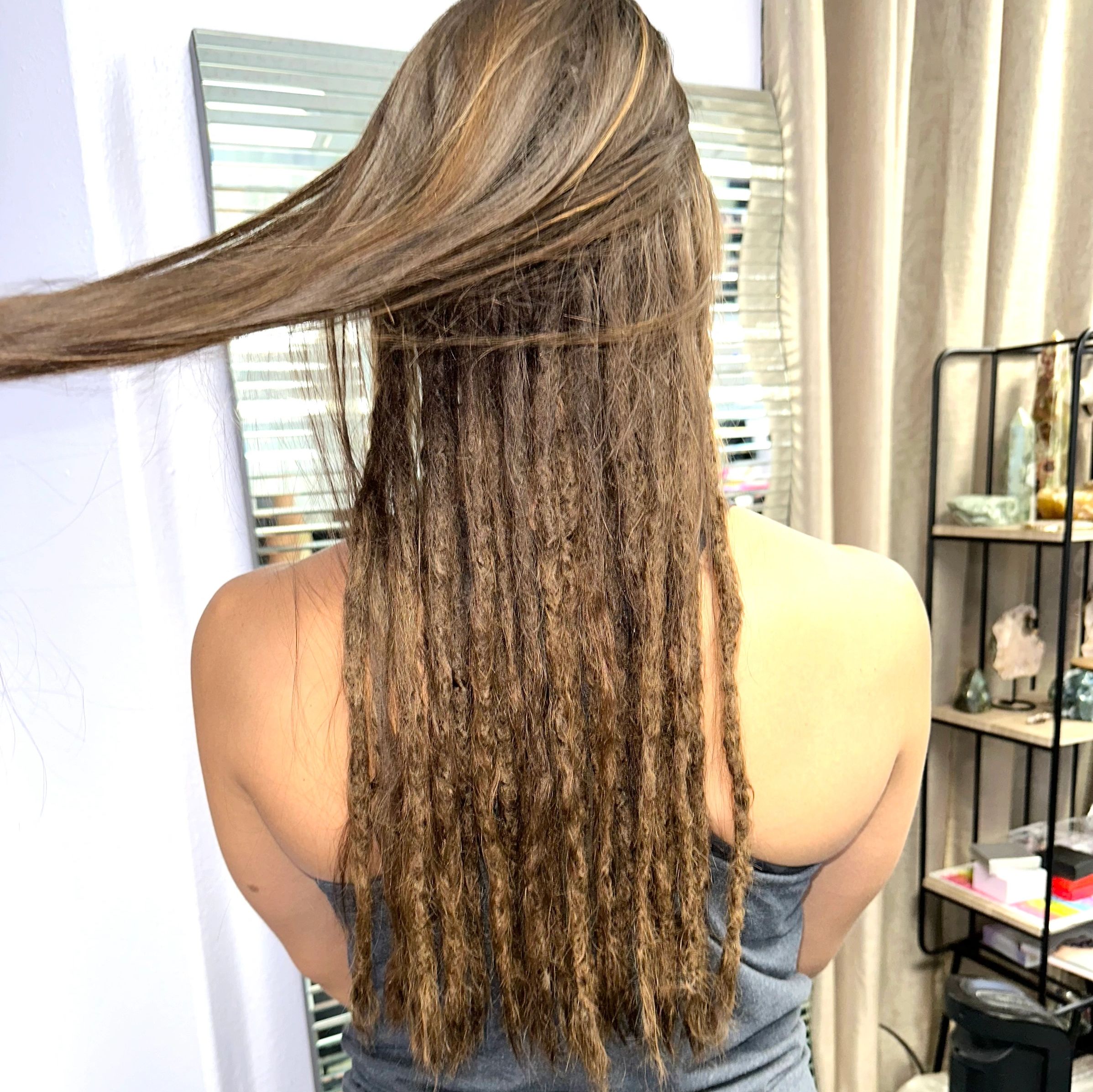 Lady, standing with back turned and half hair of dreadlocks half straight hair