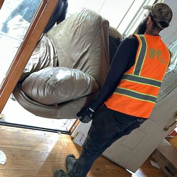 Man in safety vest carrying a chair out a door.psjunkremovalwi.