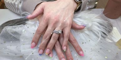 Hands with colorful french tip manicures and rings.