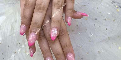Hands with pink ombré nails and white floral design.