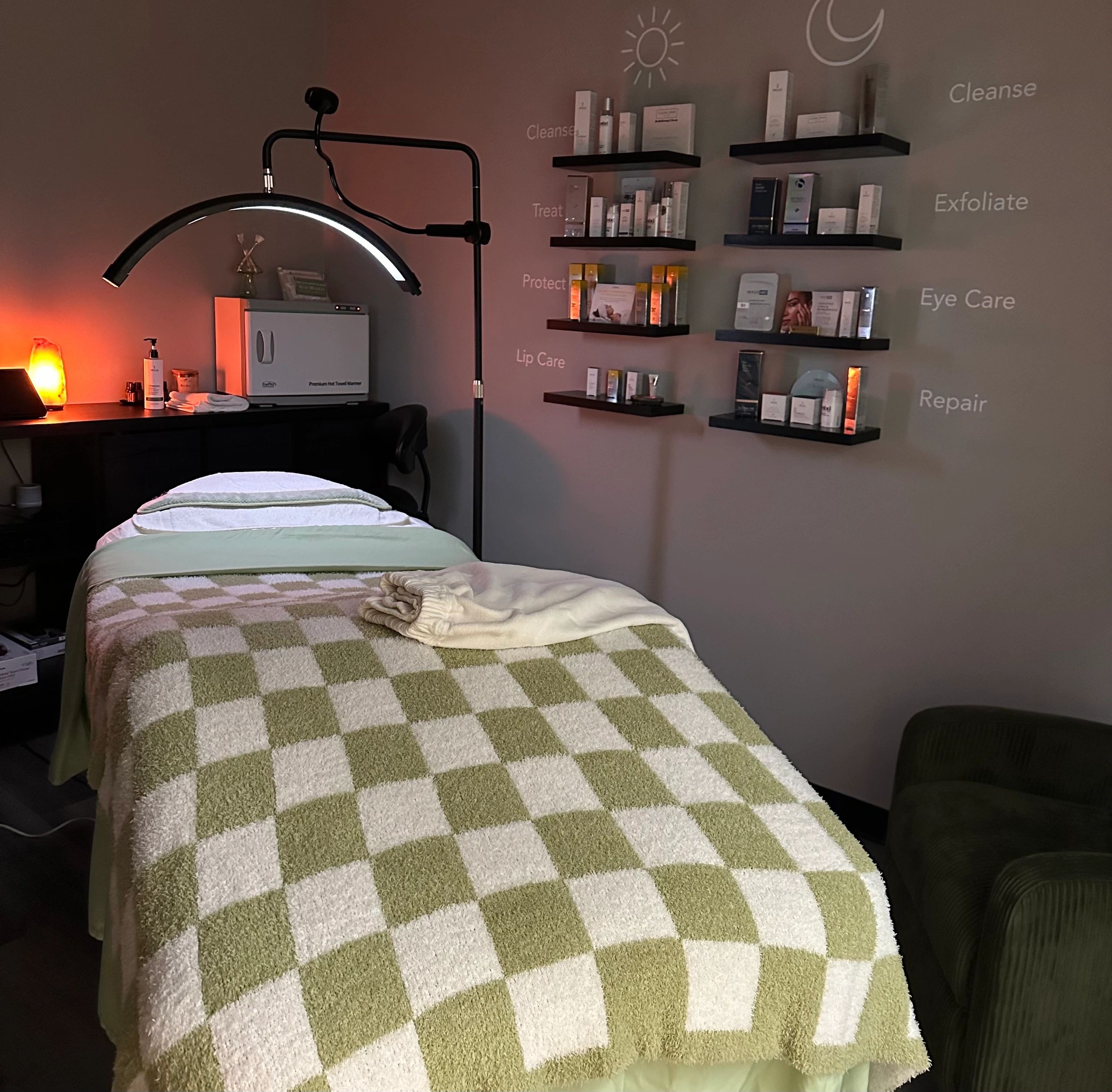 Cozy spa treatment room with neatly arranged skincare products and a checkered blanket on the massage table.