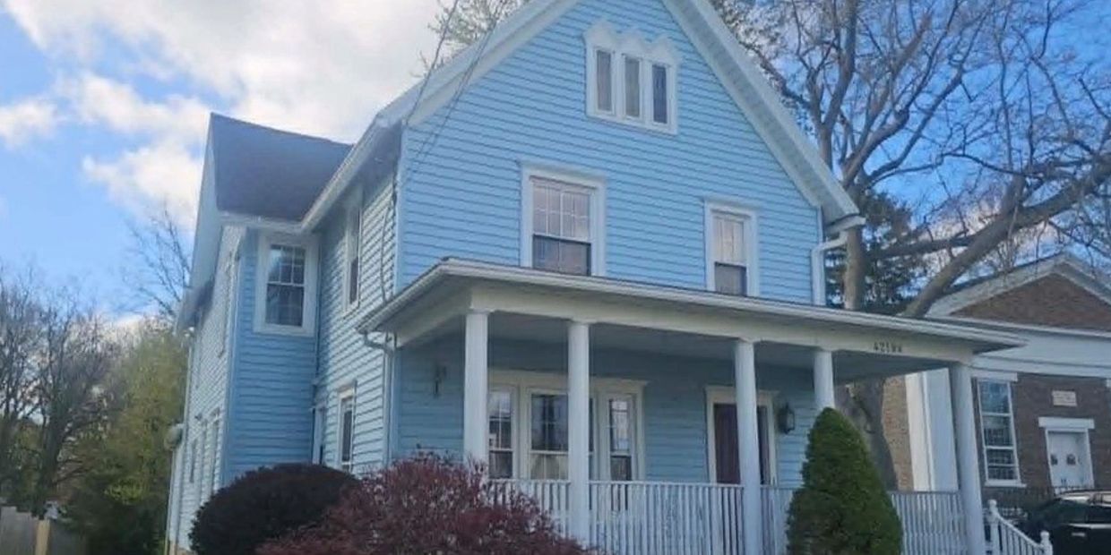 A light blue two-story house with white trim and a porch.