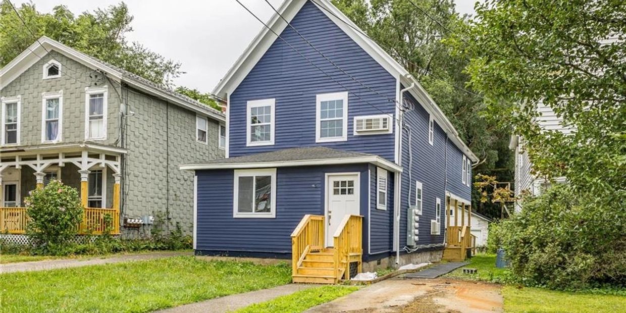 A blue two-story house with white trim and wooden porch steps.