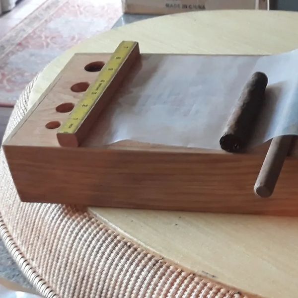 Wooden cigar rolling tray with measuring ruler and cigar.