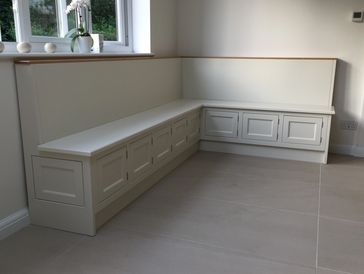 Custom white corner bench with storage cabinets beneath.