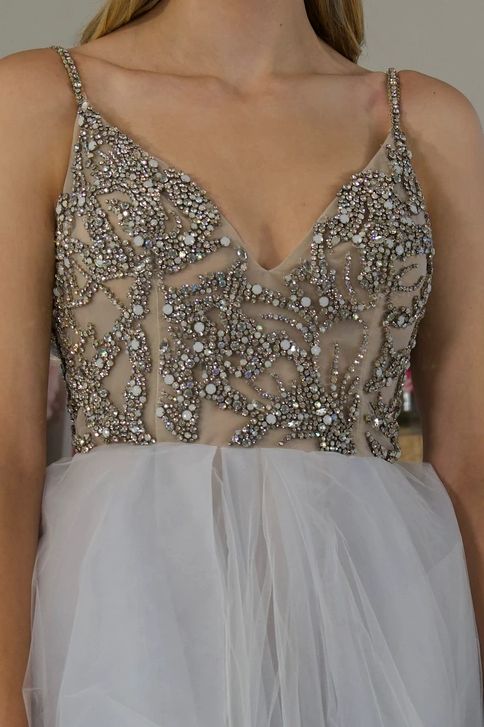 Beaded top of a white dress with spaghetti straps.