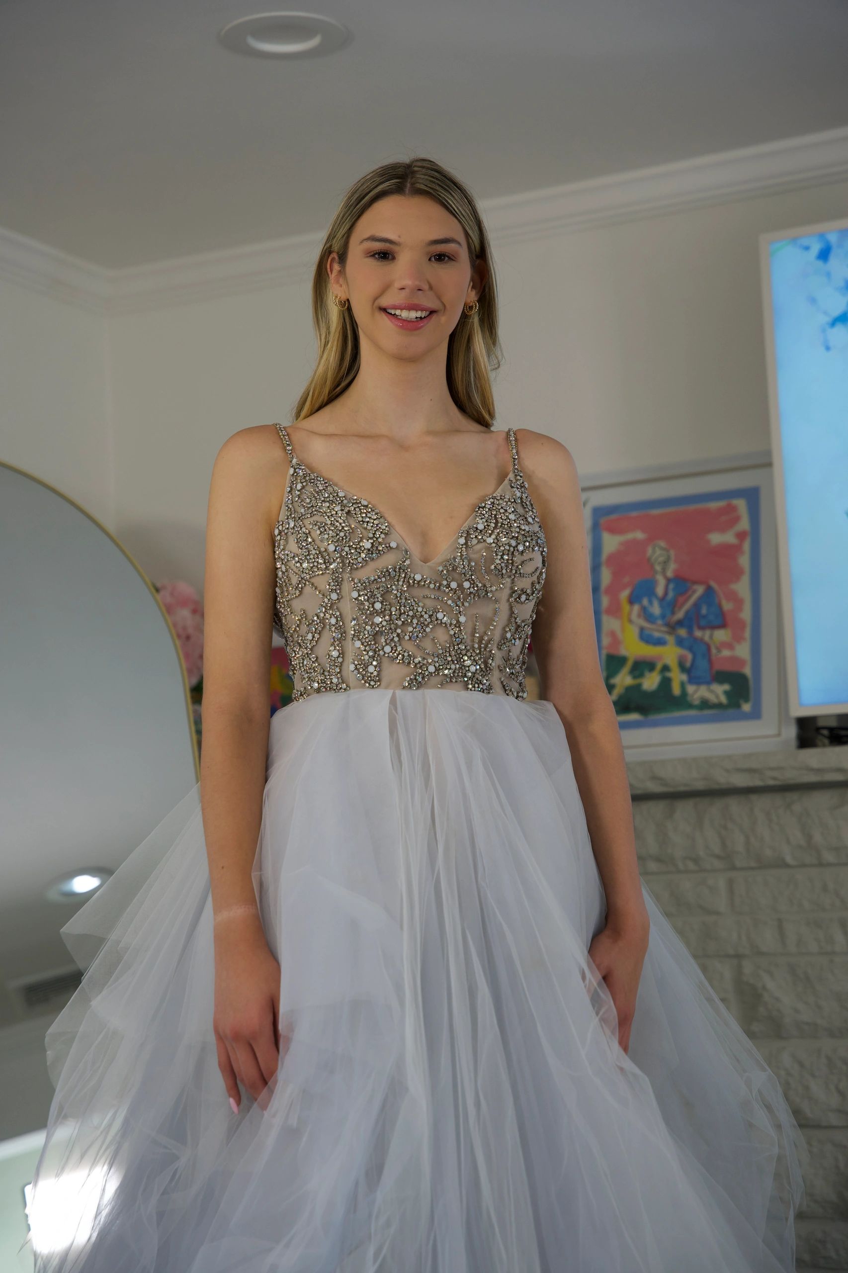 Young woman in an embellished dress smiling indoors.