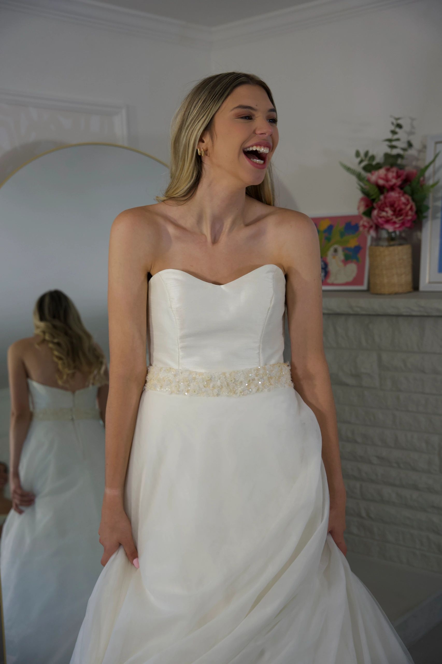 Woman in white strapless dress laughing joyfully.