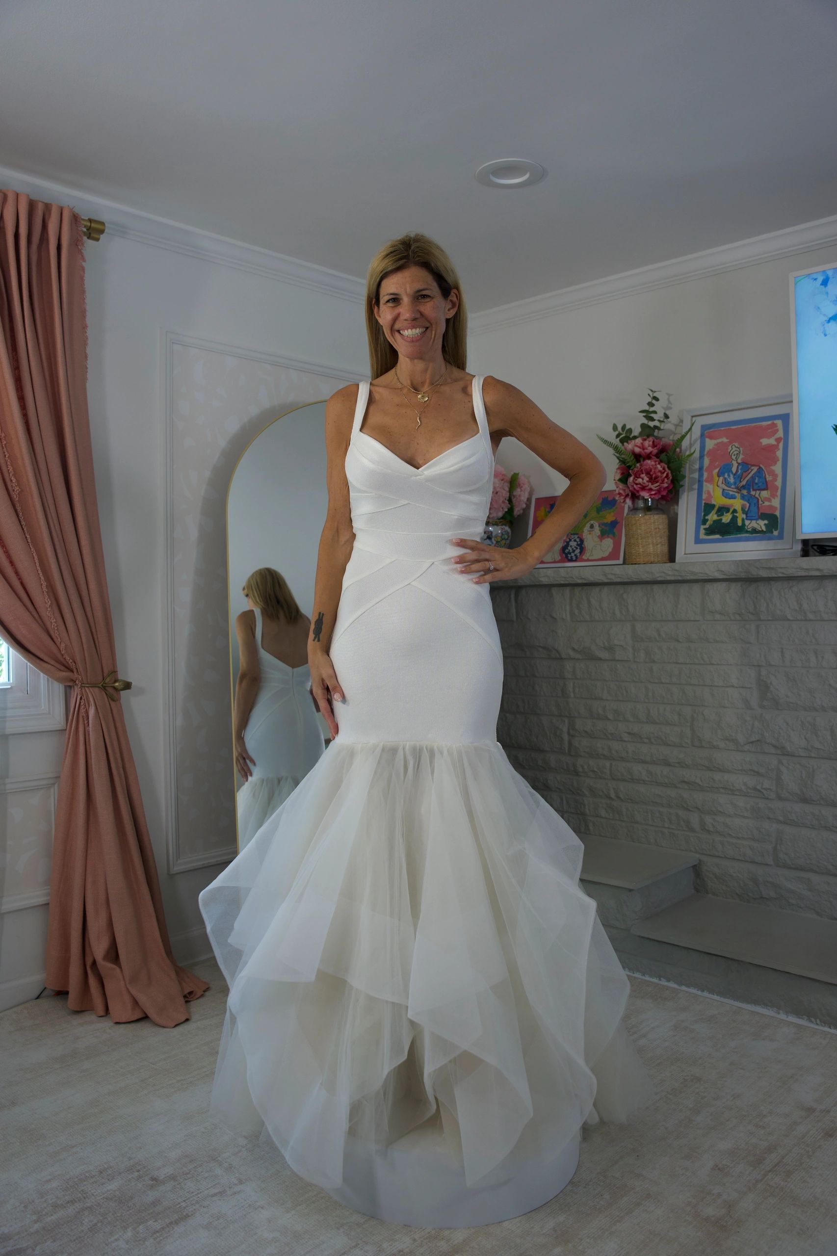 Smiling woman in a white dress standing indoors.