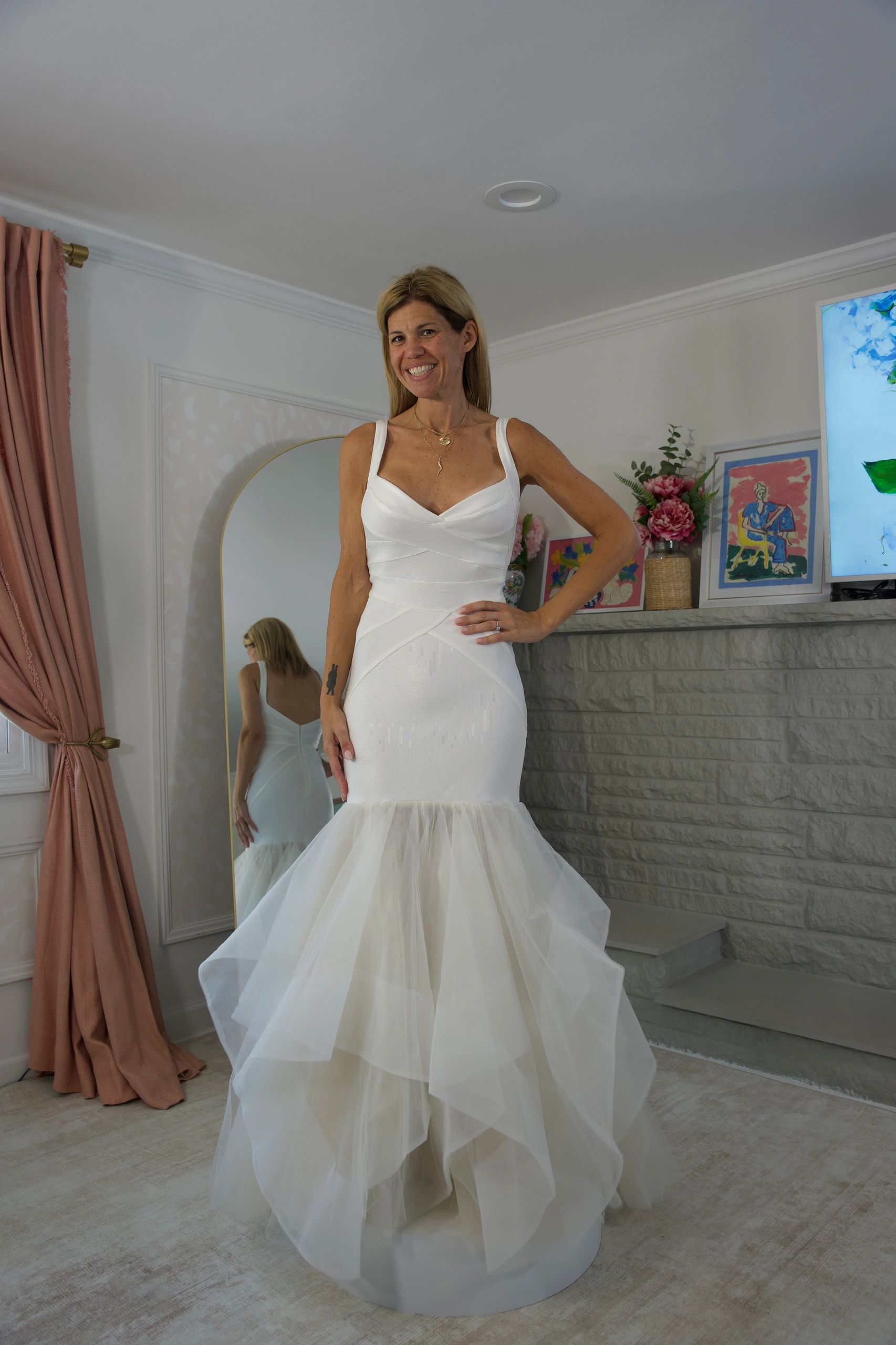 A woman smiling in a white mermaid-style dress.