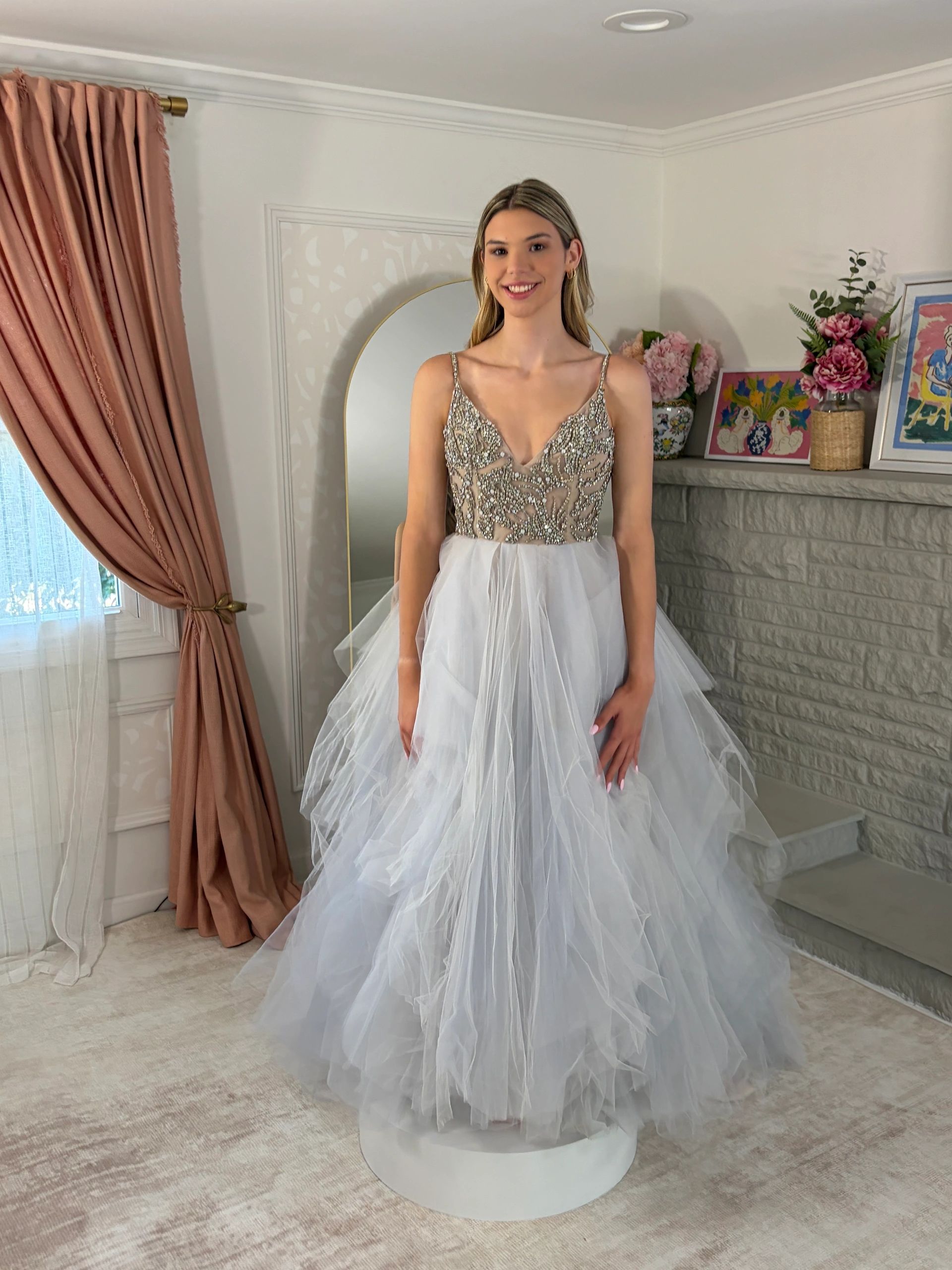 Woman in elegant silver and white dress standing indoors.