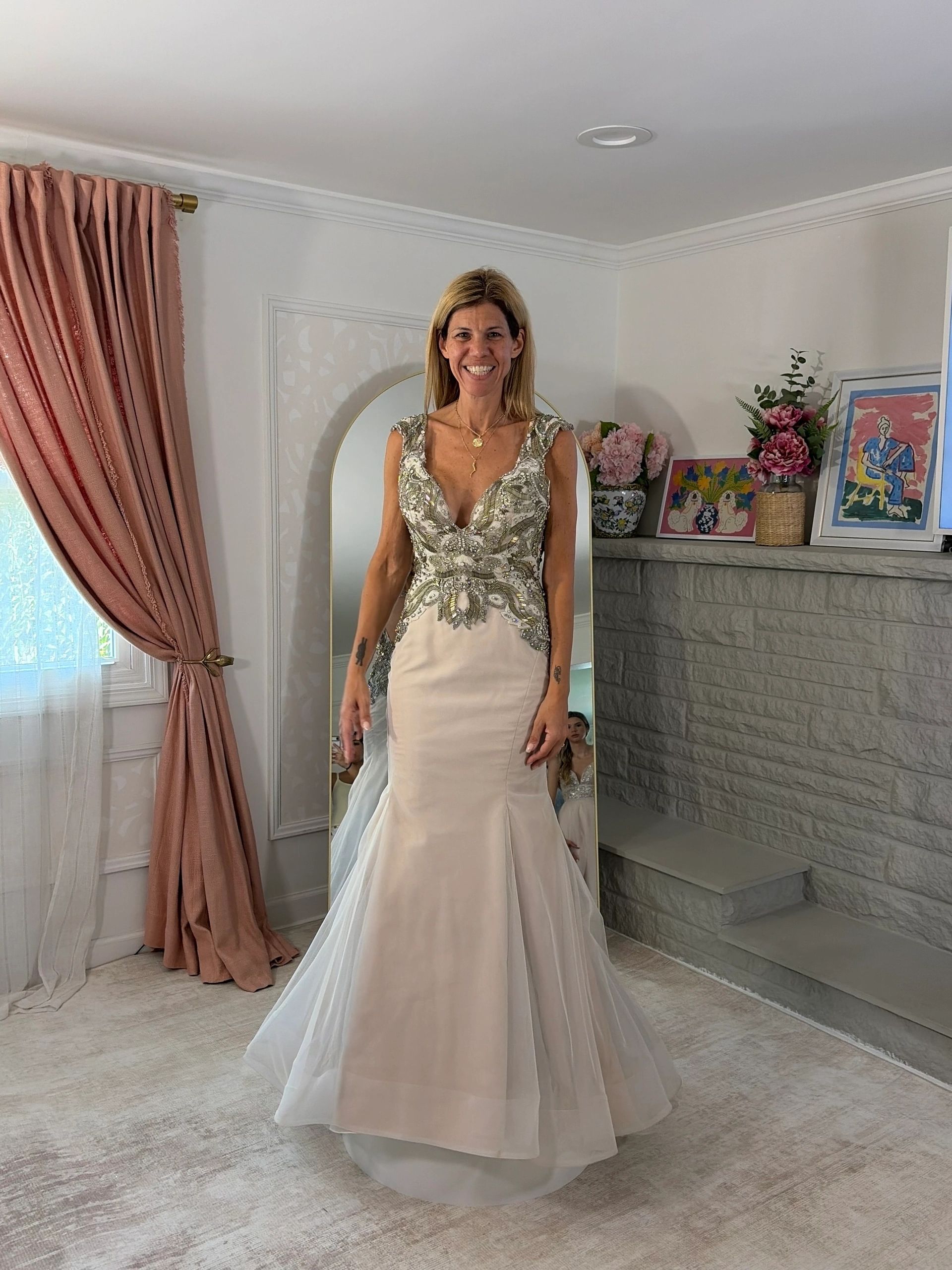 Woman smiling in a beaded wedding dress in a room.