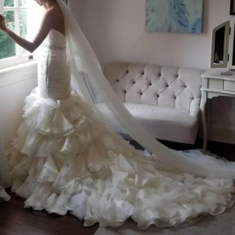 Bride in an elegant ruffled wedding gown by the window.