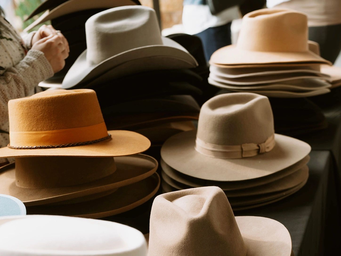 Stacks of various colored cowboy hats on display.