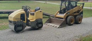 Construction equipment on a gravel path in a green field.
