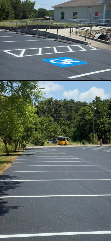 Empty parking lot with a handicap space and a distant yellow vehicle near trees.