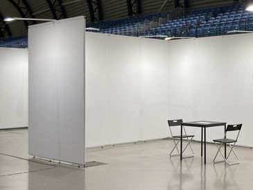 Empty exhibition booth with two chairs and a table.