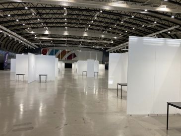 Empty exhibition booths in a large indoor event space with high ceilings.