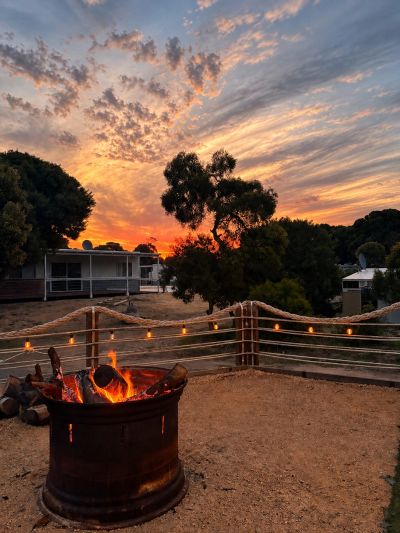 Campfire burning at sunset with colorful sky.