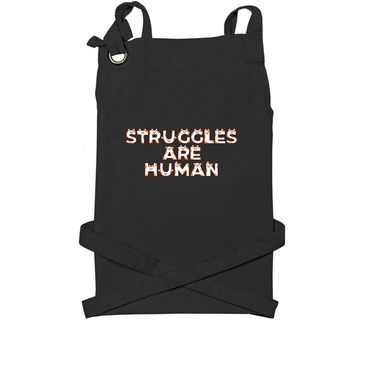 Black apron with the phrase 'STRUGGLES ARE HUMAN'.