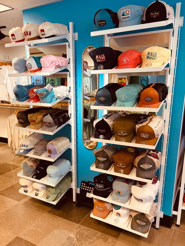 Shelves filled with colorful hats in a store with a blue wall and mirror.