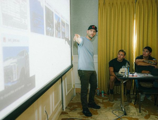 Man giving presentation to two attentive men in a room.