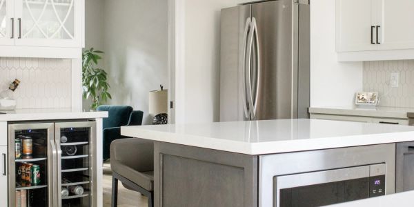 Modern kitchen with gray island and stainless steel appliances.