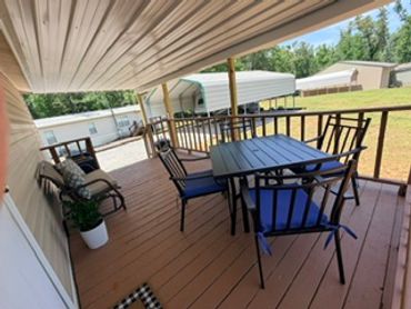 Covered patio with outdoor dining set and chairs overlooking a yard.