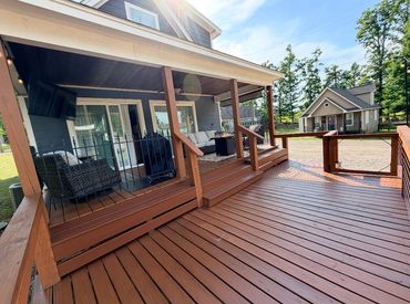 Spacious wooden deck with seating area and adjacent small cabin under a clear sky.