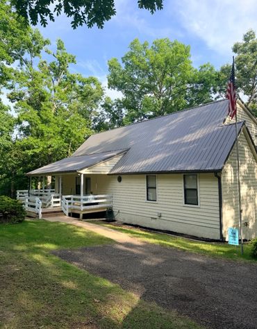 A quaint house with a metal roof and American flag under bright blue sky.