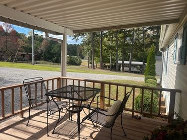 Cozy porch with metal chairs and glass table overlooking a green yard.