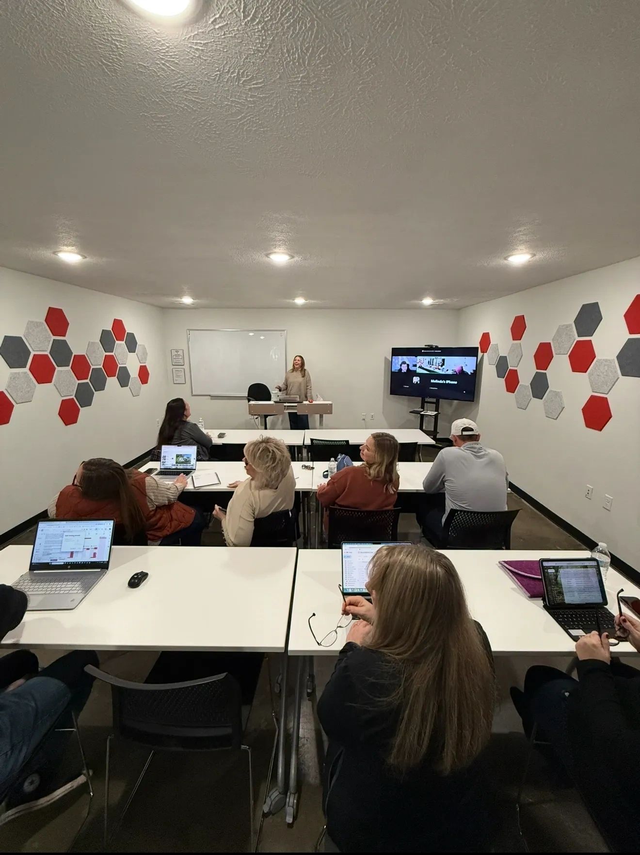 Group of people attending a hybrid meeting in a modern conference room with laptops and a presenter.