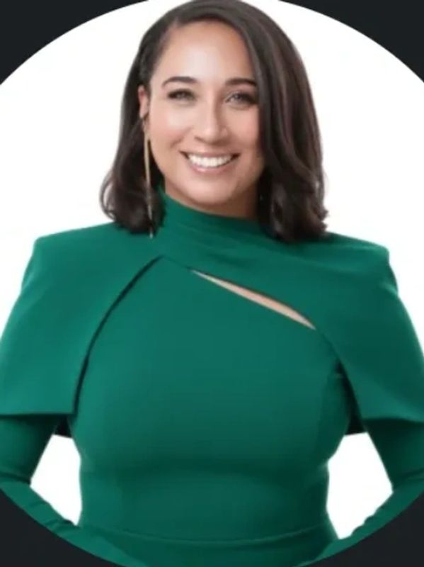 Smiling woman in a stylish green dress with cutout detail.