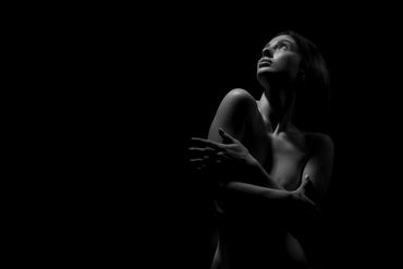 Artistic black and white portrait of a woman looking upward in dramatic lighting.
