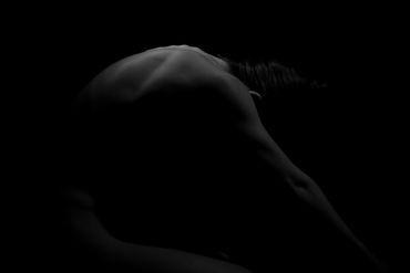 Artistic black and white photo of a nude figure with back muscles highlighted.