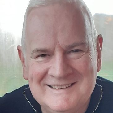 Smiling elderly man with white hair indoors.