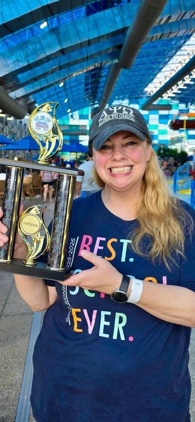 Woman smiling and holding a large trophy at an indoor water park.