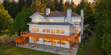 Large house with wooden deck surrounded by trees.