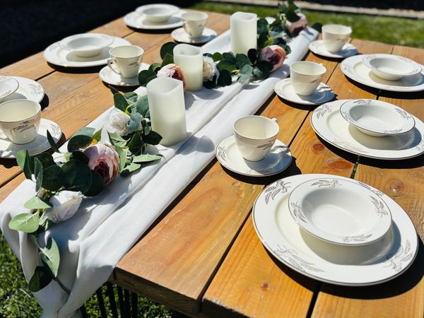 Elegant outdoor table set with white china, candles, and floral centerpiece.