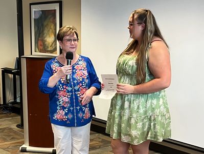 Two women engaged in a presentation or award ceremony indoors.